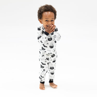 boy in a black and white glow in the dark halloween print smiling covering his mouth