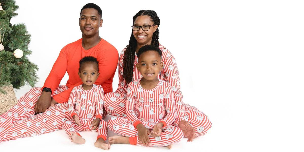A family wears matching holiday pajamas in a red and white stripe with vintage Santa Claus face print.