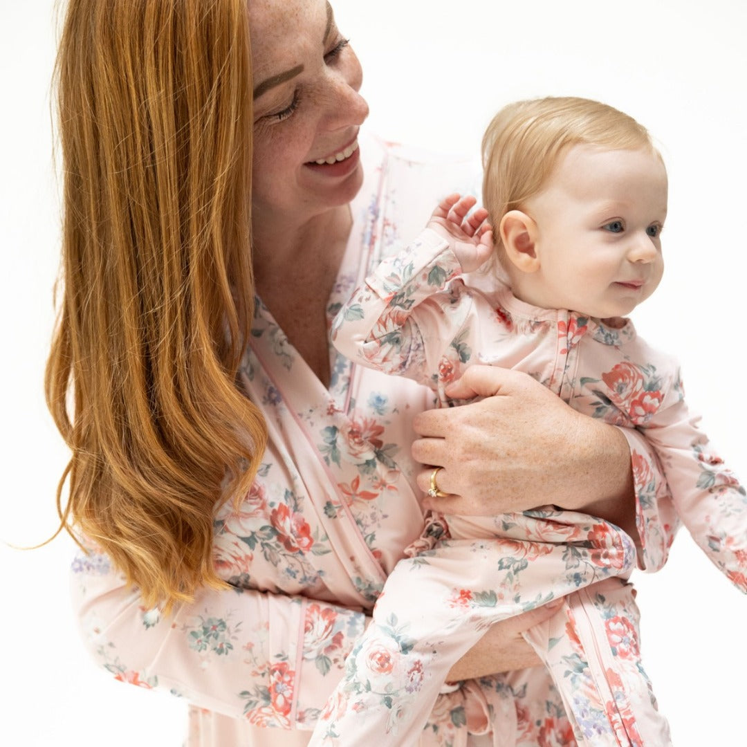 A mother holds her baby girl. They both wear styles in a matching light print and rose print. Mom wears a bamboo robe and abby wears a bamboo zipper footie.