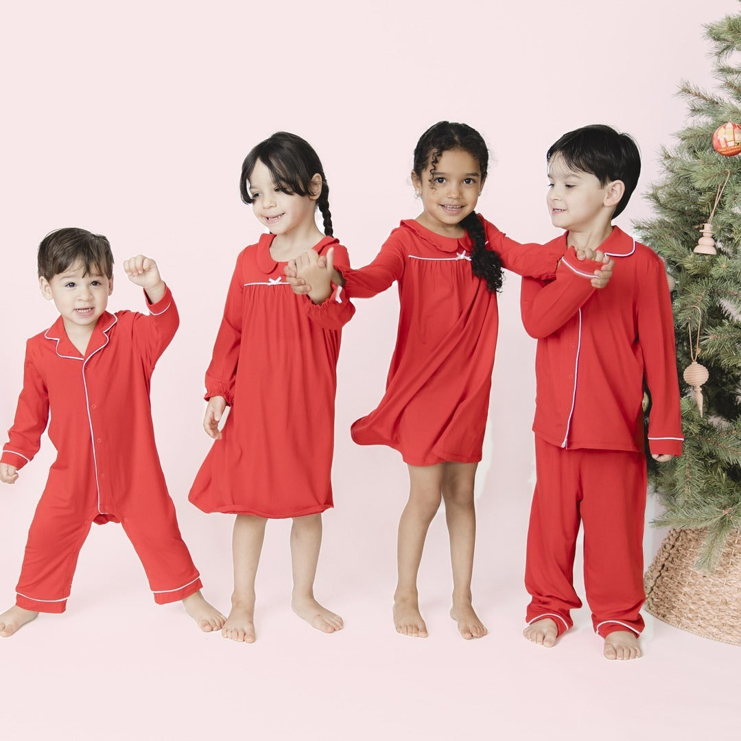 Four siblings wear matching bamboo pajamas in classic holiday red with white piping. The two sisters int he middle wear nightgowns.