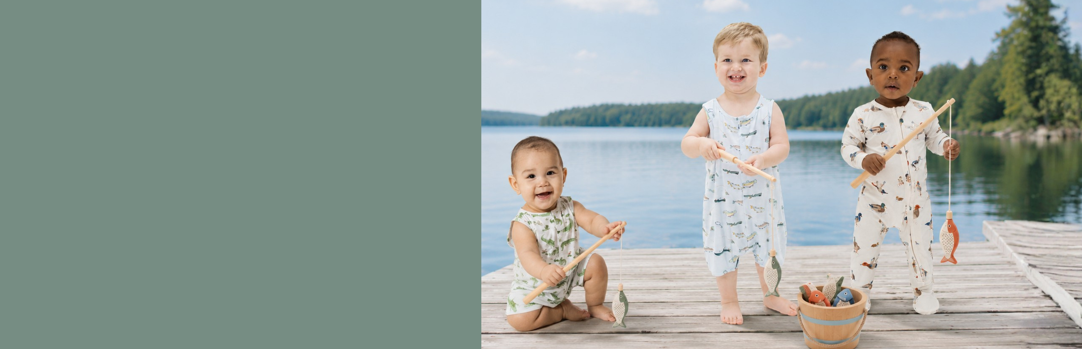 Three children in matching outdoor themed outfits standing on a dock by a lake with trees in the background.