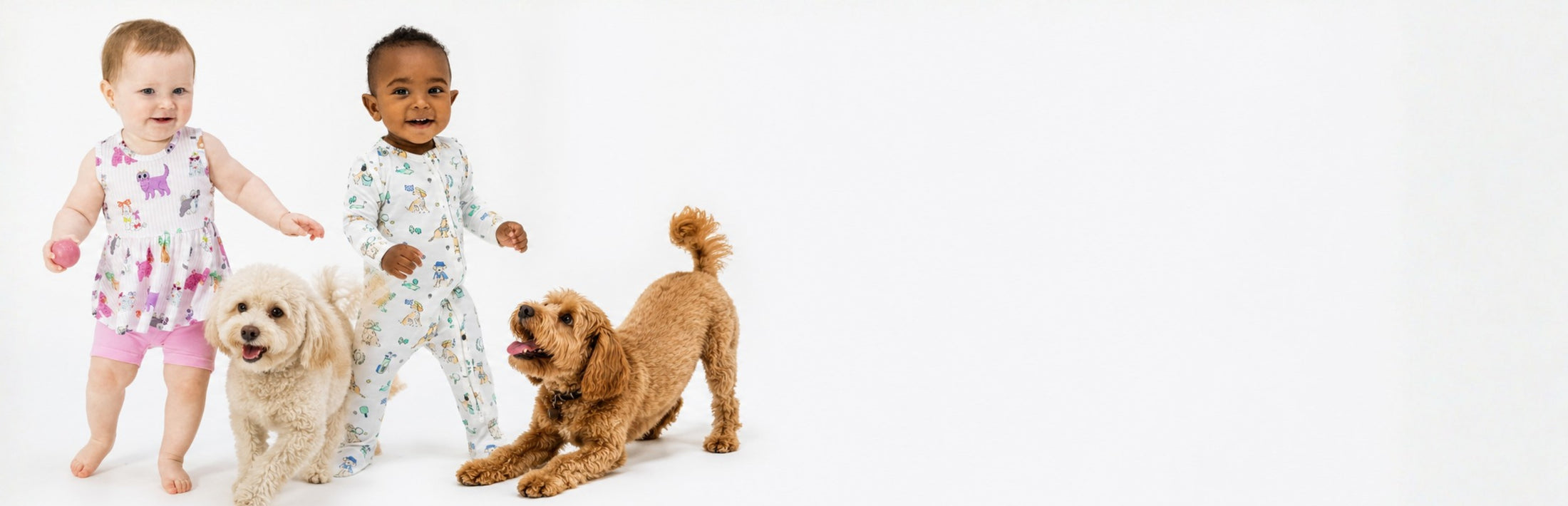 Two toddlers wearing clothing with dog illustrated prints and two dogs on a white background