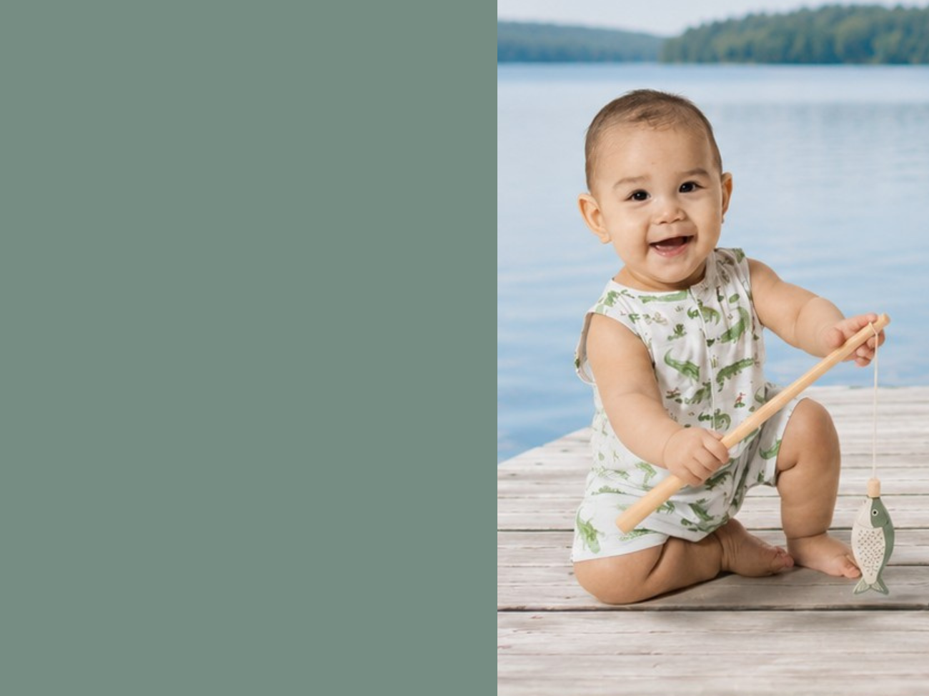Baby sitting on a dock by a lake, holding a wooden fishing toy, wears a bamboo short romper with an illustrated all-overalligator print.