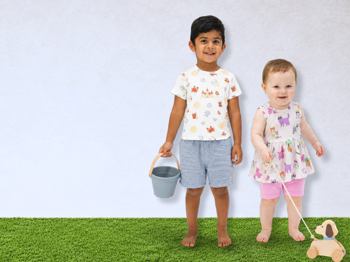 Two children standing on a grassy patch with a white background all wearing summer outfits.