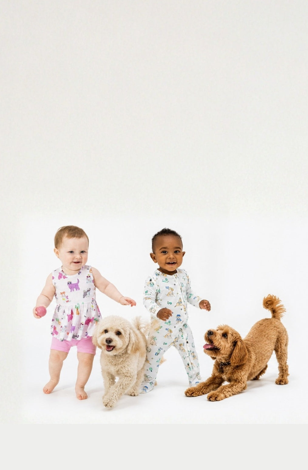 Two toddlers wearing clothing with dog illustrated prints and two dogs on a white background